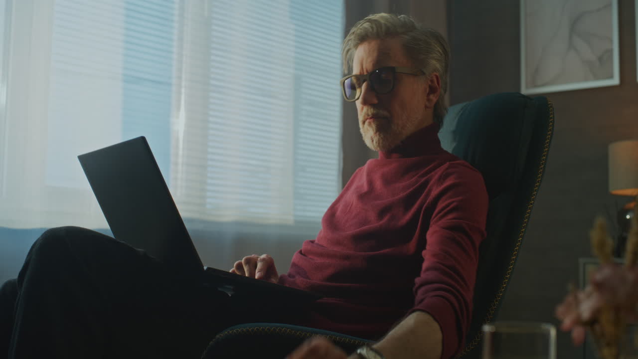 Modern Businessman in Red Turtleneck Enjoys Coffee and Breakfast While Working on Laptop in Hotel (Stock Footage)