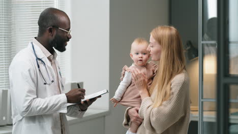 doctor consulting woman with baby in clinic