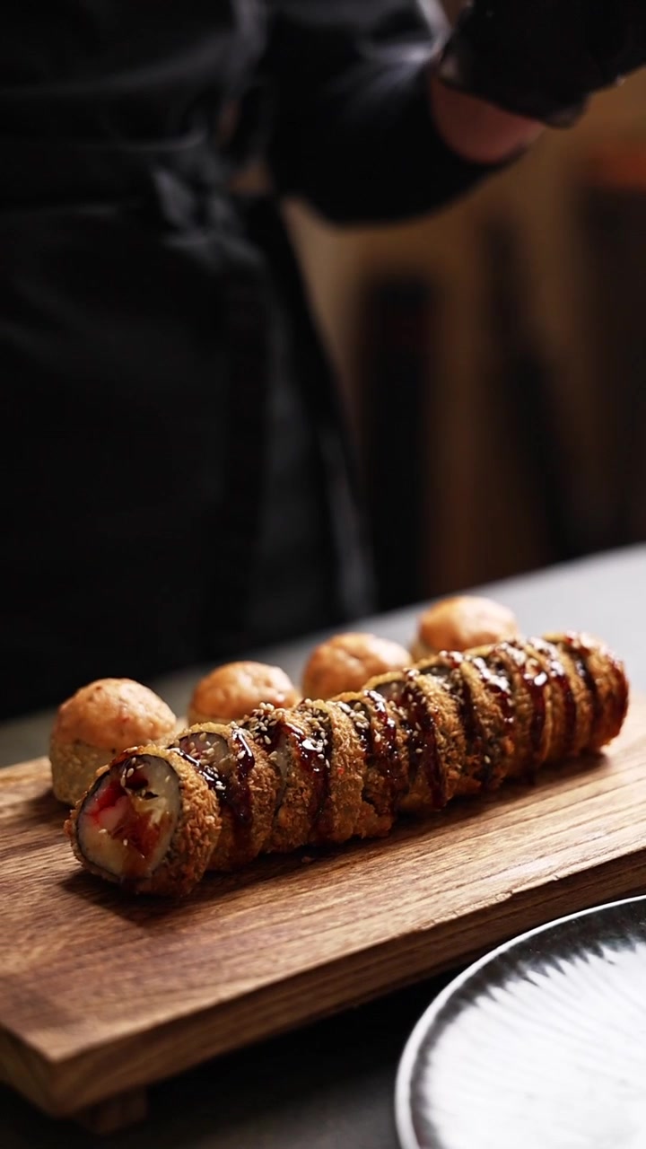 Chef Arranging Delicious Deep-Fried Sushi Rolls on a Wooden Board