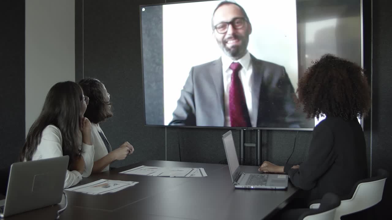 jefe de mediana edad saludando a los empleados a través de video chat y hablando