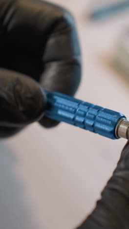 una vista de cerca de las manos con guantes de un técnico ajustando un tornillo mientras trabaja en una placa de circuitos bajo un microscopio