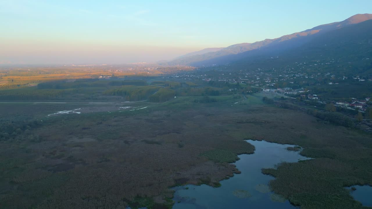 Aerial of wide river winding through valley at sunset with golden light on landscape