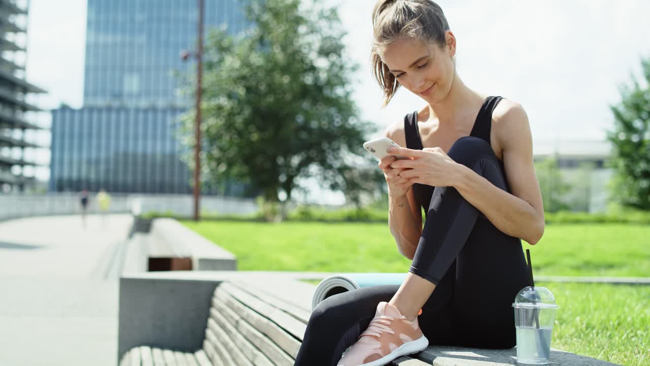 video de una mujer joven escribiendo mensajes en el teléfono al aire libre