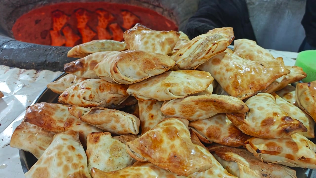 Chef che rimuove Samsa appena sfornati dal forno tandoor.