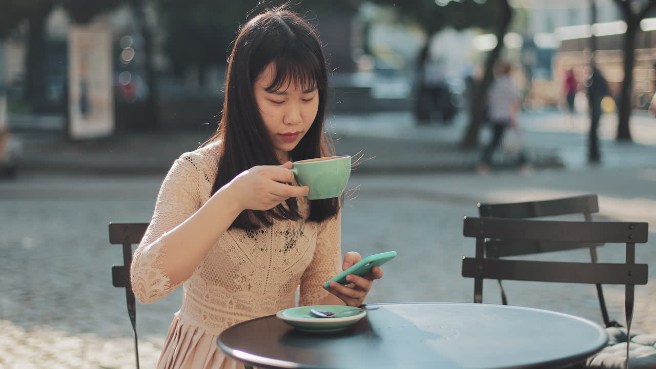 Woman enjoying coffee and using her phone at an outdoor cafe