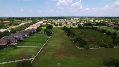 aerial of residential area with green lawns, trees, and winding roads under daylight