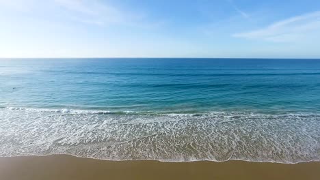 cool ocean waves washing against spanish beach golden sandy beachfront aerial view dolly left