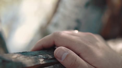 young man nervously knocks his fingers on the wooden railing close-up slow motion