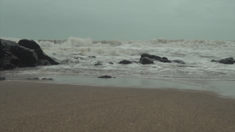 strong waves splashing and crashing on the sand at a rocky beach in monsoon