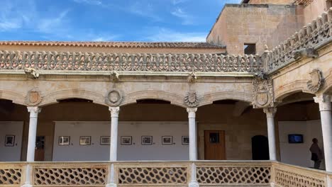 filming of the first floor through the interior patio of la casa de las conchas where we see on the walls that there is an exhibition of photographs, there is a man observing them on a sunny afternoon