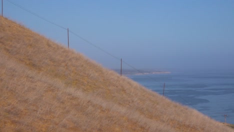 panorámica desde el océano pacífico hasta una pareja montando caballos en un sendero en un rancho en santa bárbara, california