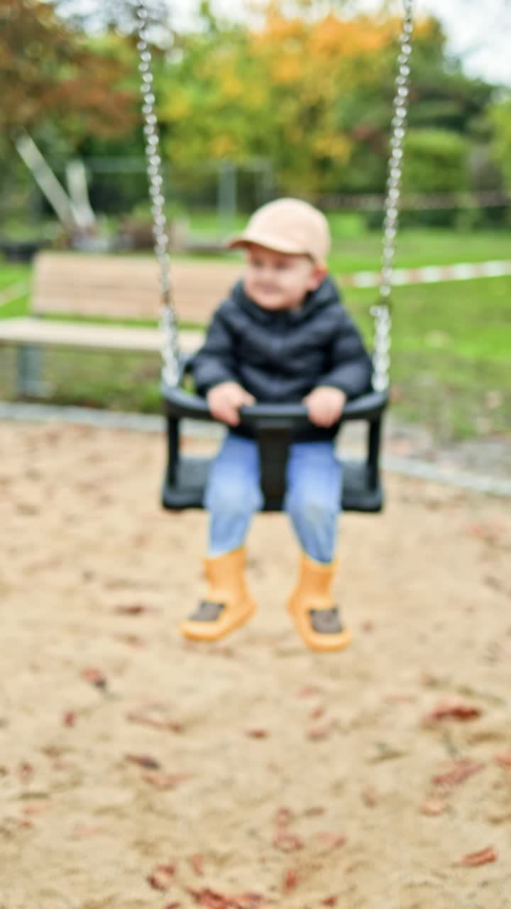 Bambino piccolo che si dondola su un'altalena in un parco giochi. Un bimbo che si dondola su un'altalena in un parco cittadino. Bambino che gioca all'aperto nella natura.