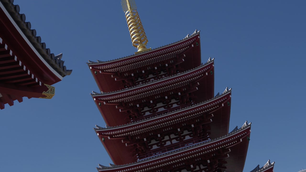 Gestufte rote Pagode mit goldener Spitze ragt vor klarem blauem Himmel in Tokio auf