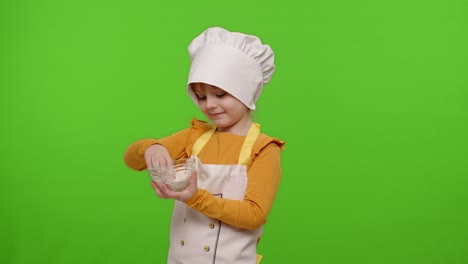 niña niño vestido cocinero cocinero panadero en delantal y sombrero agitar la harina en un plato, tonteando