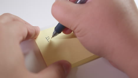Writing-the-words-for-sale-on-a-piece-of-sticky-notes-paper,-using-a-black-ballpen