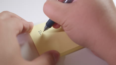 writing the words for sale on a piece of sticky notes paper, using a black ballpen