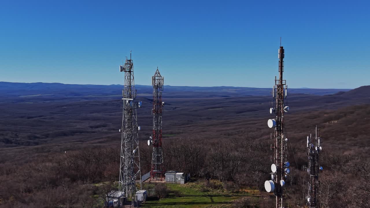 Tall communication towers stand on a hilltop in a remote area
