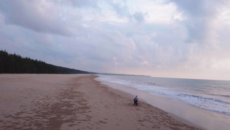 aerial view of a motorcycle on the beach with a sunset in background