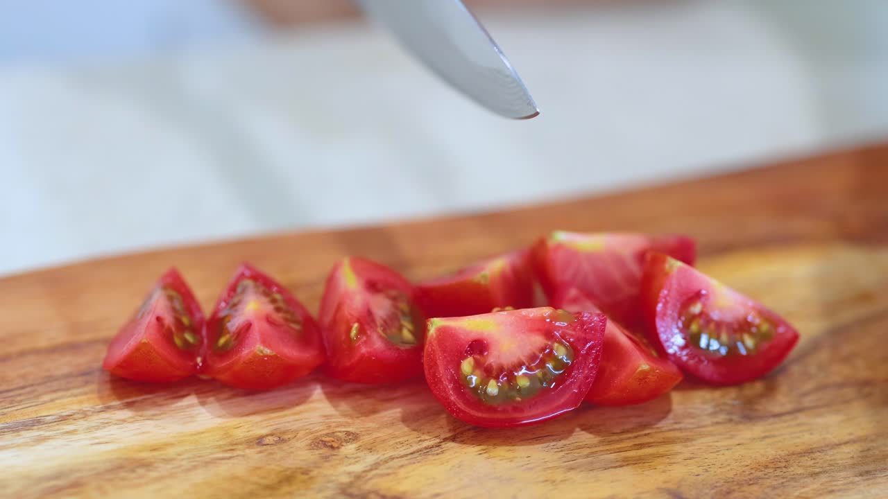 Close-up of hands slicing ripe tomatoes on a wooden board. Bright lighting enhances the fresh, vibrant colors