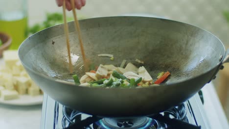 mujer freyendo hongos y verduras en una sartén