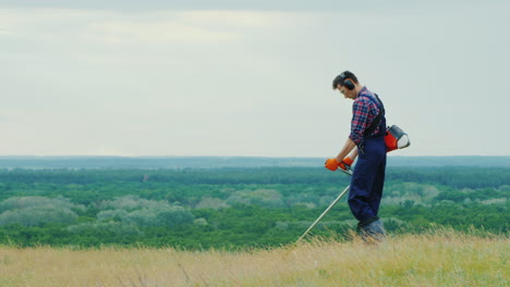 Young-Man-Mowing-Grass-With-A-Trimmer-On-A-Picturesque-Meadow