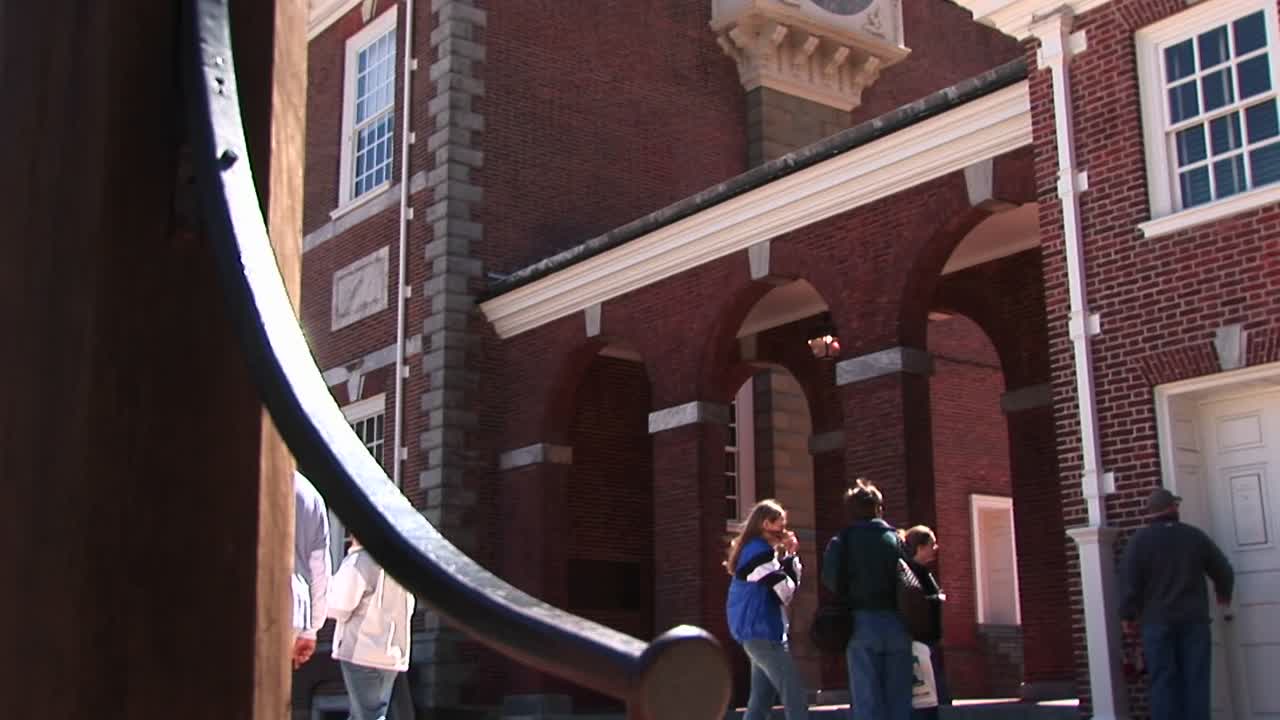 la cámara se desplaza desde el nivel de la calle hasta la esfera de un reloj al costado del salón de la independencia de filadelfia