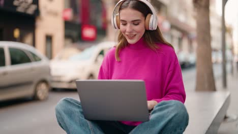 young blonde woman listening to music and dancing at street