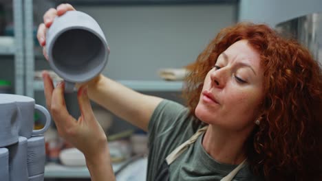 woman inspecting handmade pottery mugs in a pottery studio