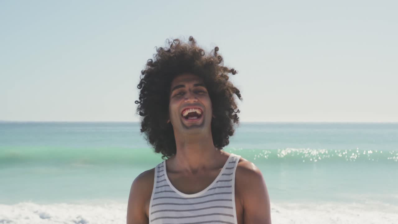 Mixed race man looking at the camera and laughing at beach