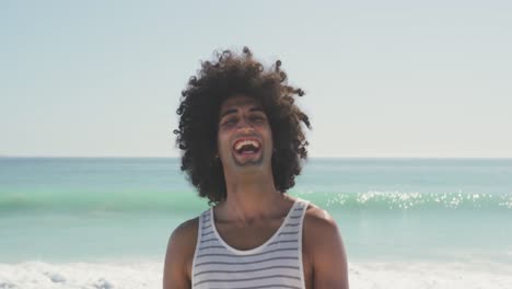 hombre de raza mixta mirando a la cámara y riendo en la playa