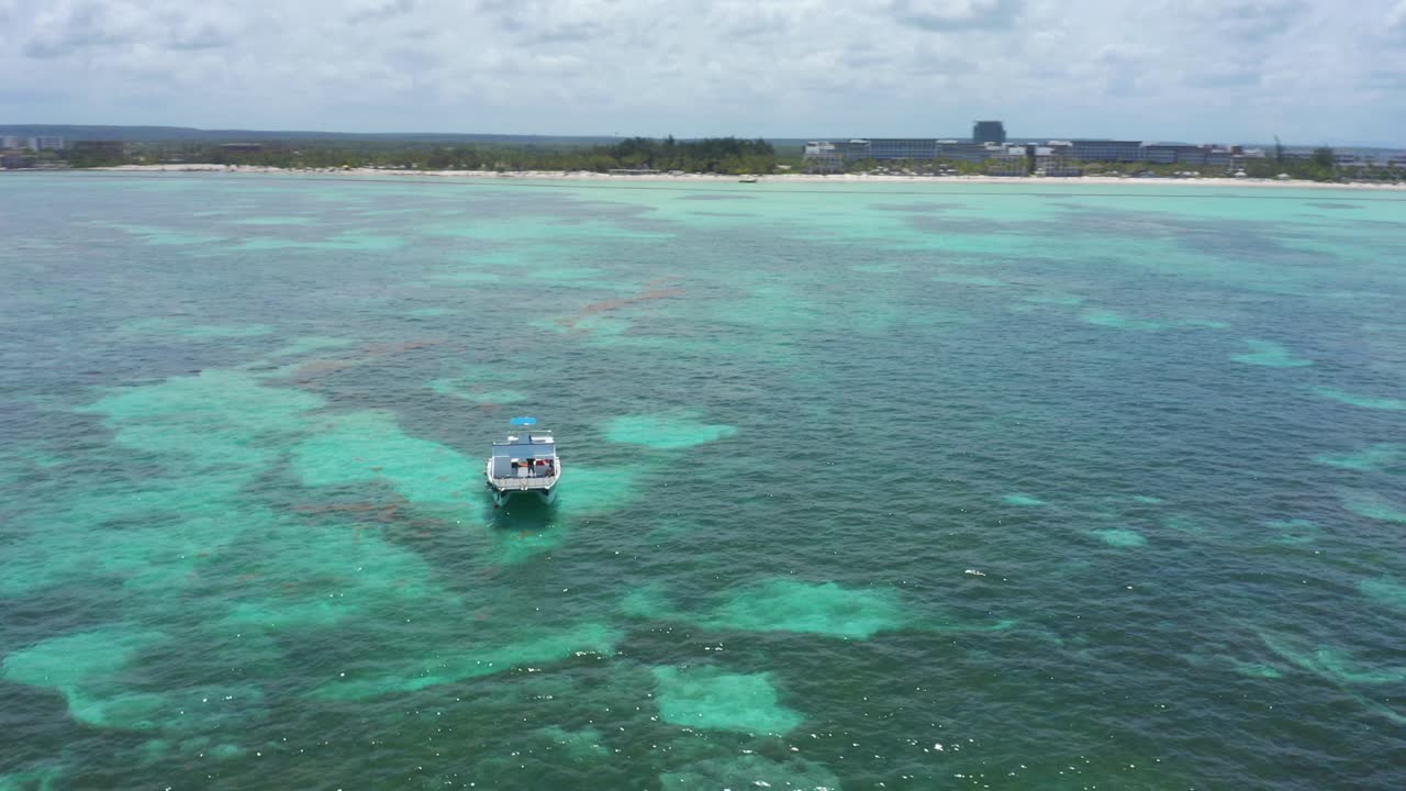 lancha de un solo motor anclada en aguas turquesas del océano en la playa de juanillo, cap cana, república dominicana, sobre la antena del círculo