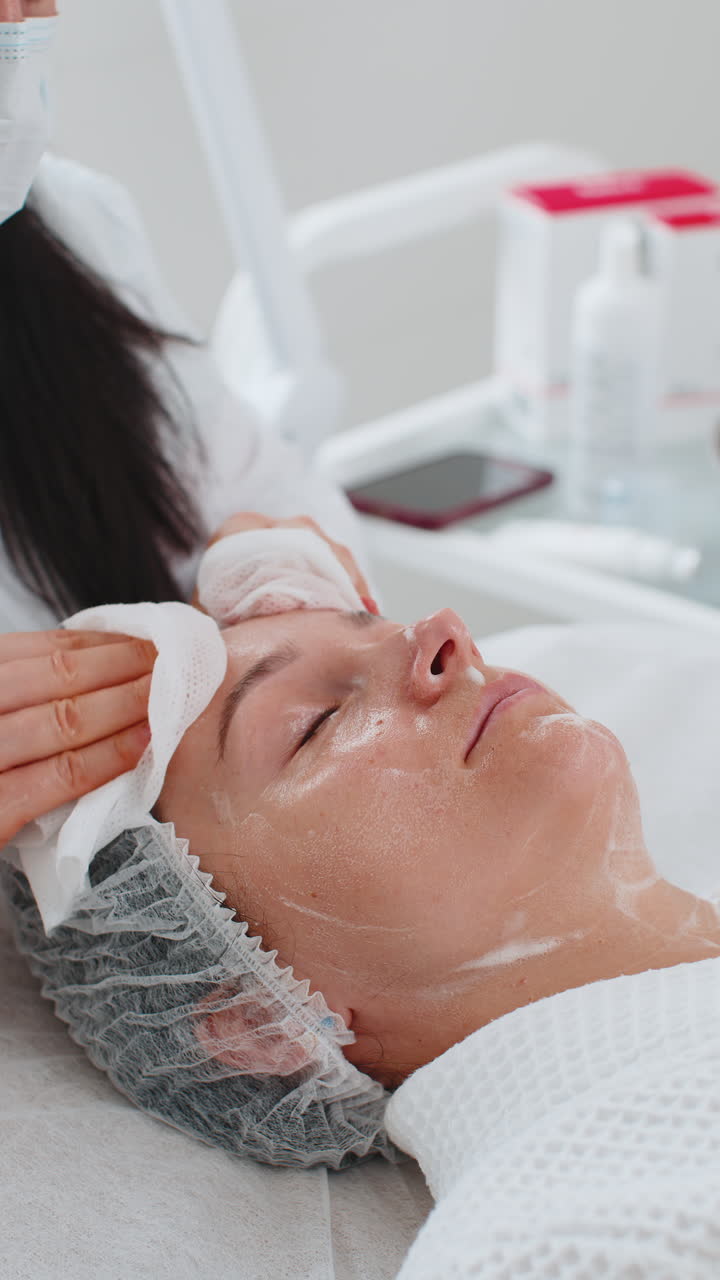cosmetólogo médico limpia la cara y el cuello de la mujer procedimiento de limpieza con toallitas de algodón en la clínica de belleza