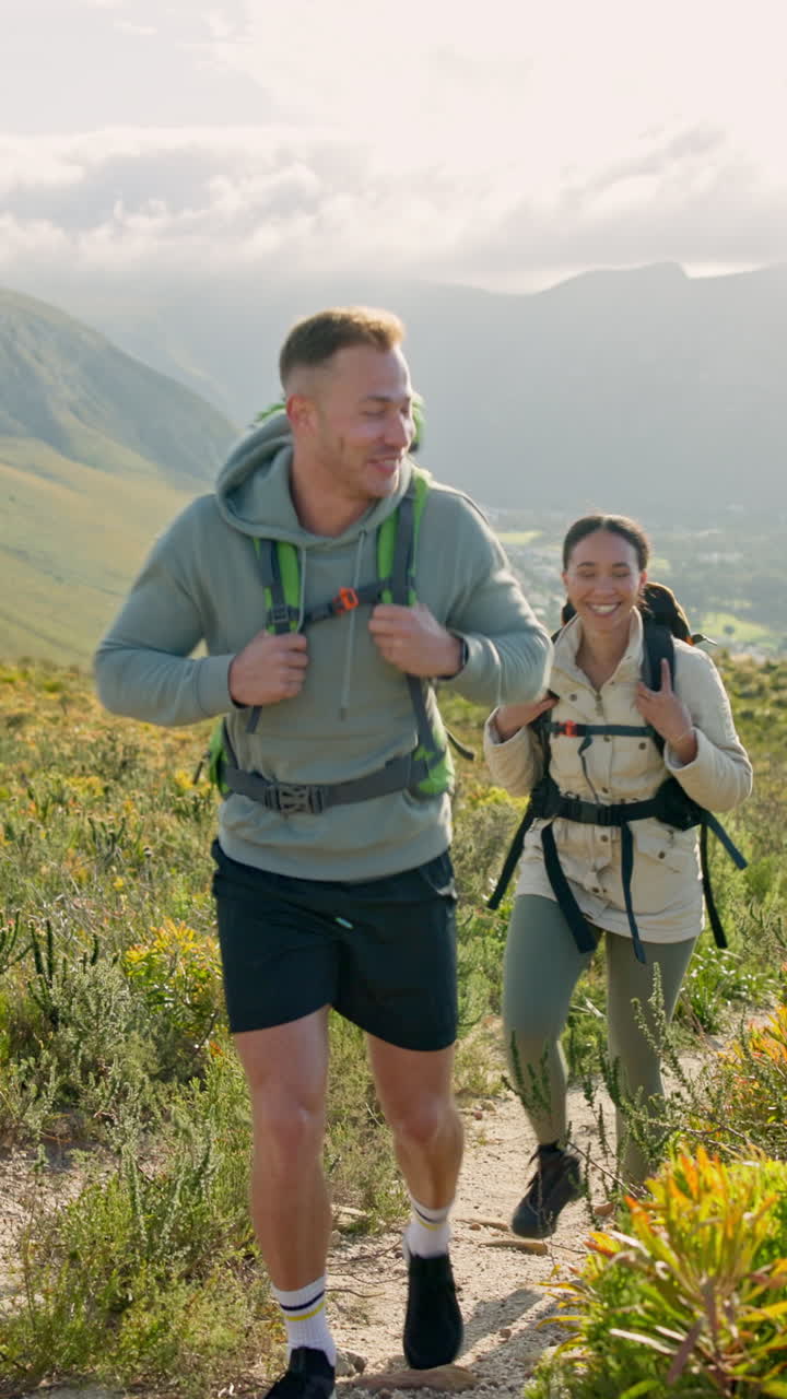 Coppia felice che fa trekking su un sentiero di montagna con gli zaini.