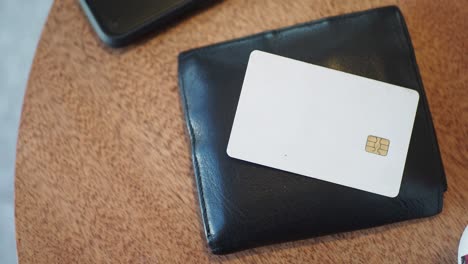 close-up of a white credit card with a chip and pin in a black leather wallet