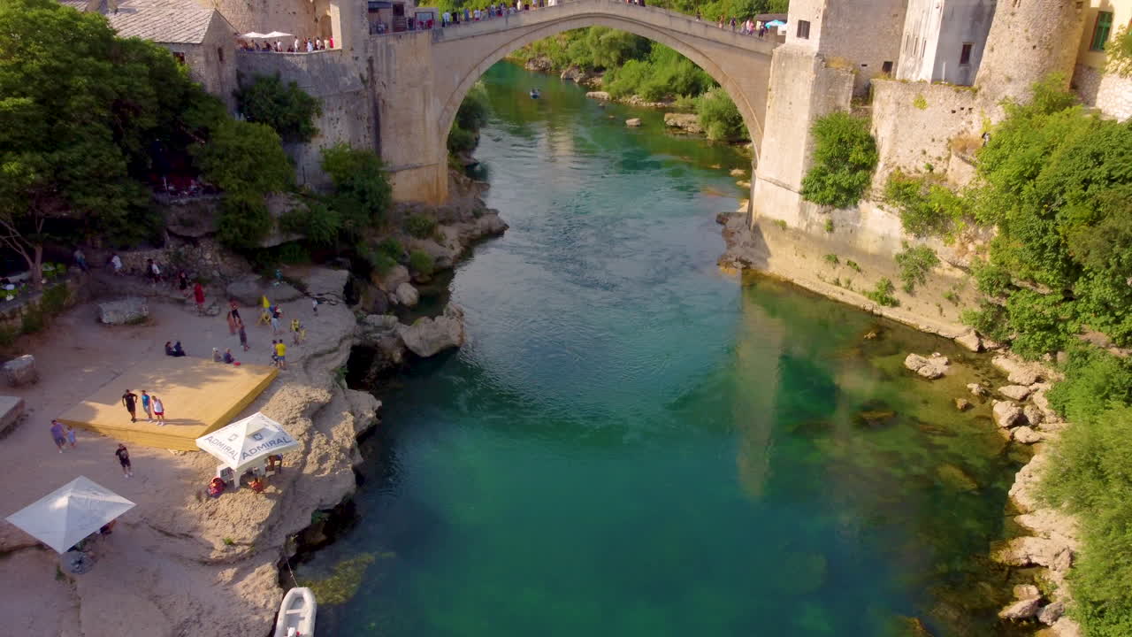 모스타르, 보스니아 헤르체고비나의 배경에 코스키 메흐메드 파샤 모스크가 있는 네레트바 강 너머의 스타리 대부분에 있는 사람들의 공중 전망