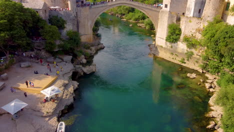 aerial view of people at stari most over neretva river with koski mehmed pasha mosque in background in mostar, bosnia and herzegovina