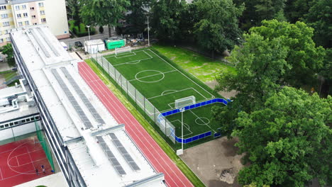 flying towards a brand new football field mad with artificial grass next to the elementary school in poland, 4k drone