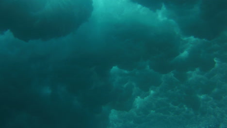 rise up from underwater ocean surface with storm cloud patterns of whitewash on water