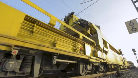 maquinaria ferroviaria amarilla especializada trabajando en las vías durante el día, filmada en la brillante luz del sol