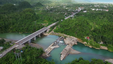 picturesque aerial orbit of scenic river crossing bridge and concrete dam at lush tropical island village - virac, catanduanes, philippines