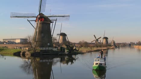 a boat moves along a canal in holland with windmills nearby 4