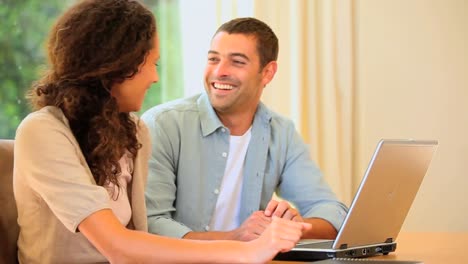 una encantadora pareja joven usando una computadora portátil
