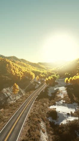 a winding mountain road through a forest during golden hour