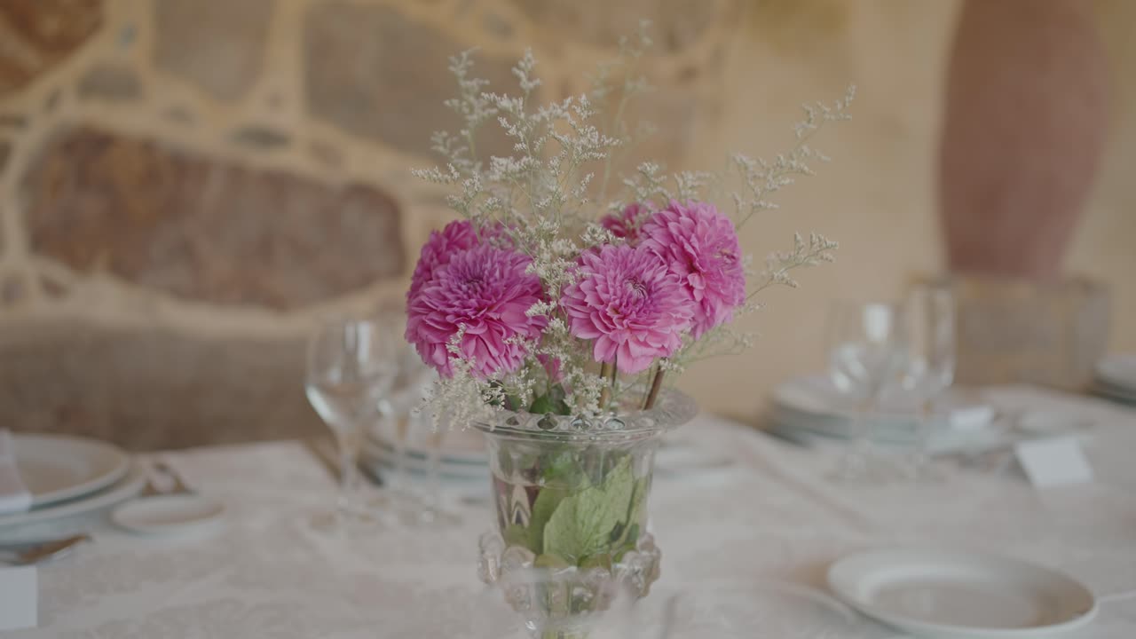 Розовые цветы в прозрачной вазе украшают яркий свадебный стол