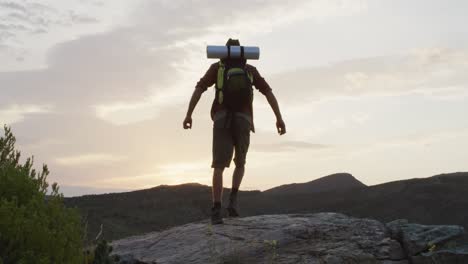 Caucasian-male-survivalist-with-arms-in-the-air,-celebrating-reaching-mountain-peak-in-wilderness