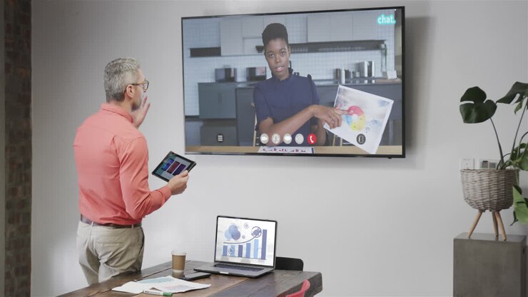 Caucasian businessman on video call with african american female colleague on tv screen