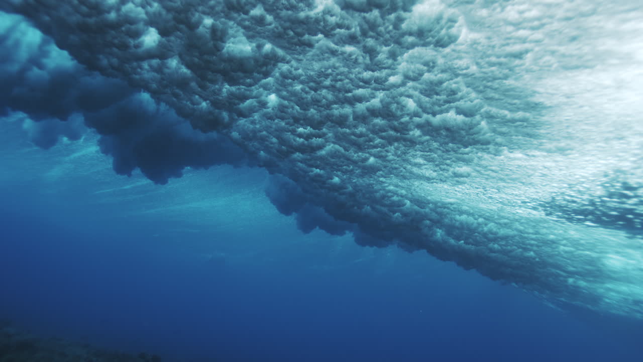 Underwater mist and spray foam spreads out across surface in dramatic dark cloud, slow motion