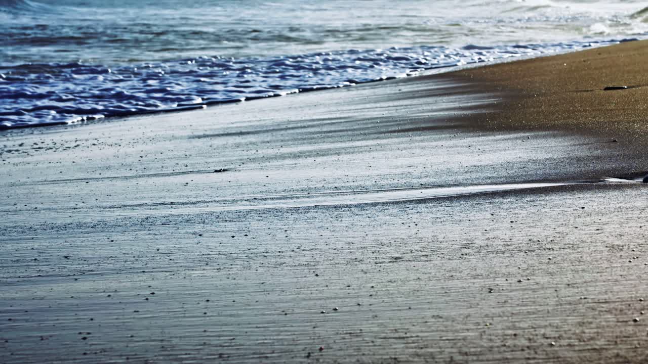 모래 해변을 때리는 슬로우 모션 파도