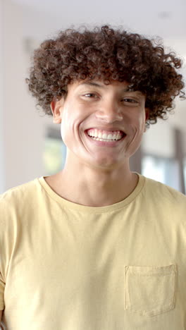 vertical video: smiling young man in yellow shirt enjoying time with friends indoors