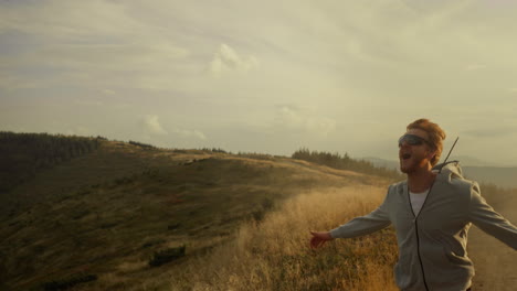 Müder-Jogger-Läuft-In-Der-Berglandschaft.-Lächelnder-Kerl,-Der-Im-Freien-Die-Hände-Hebt